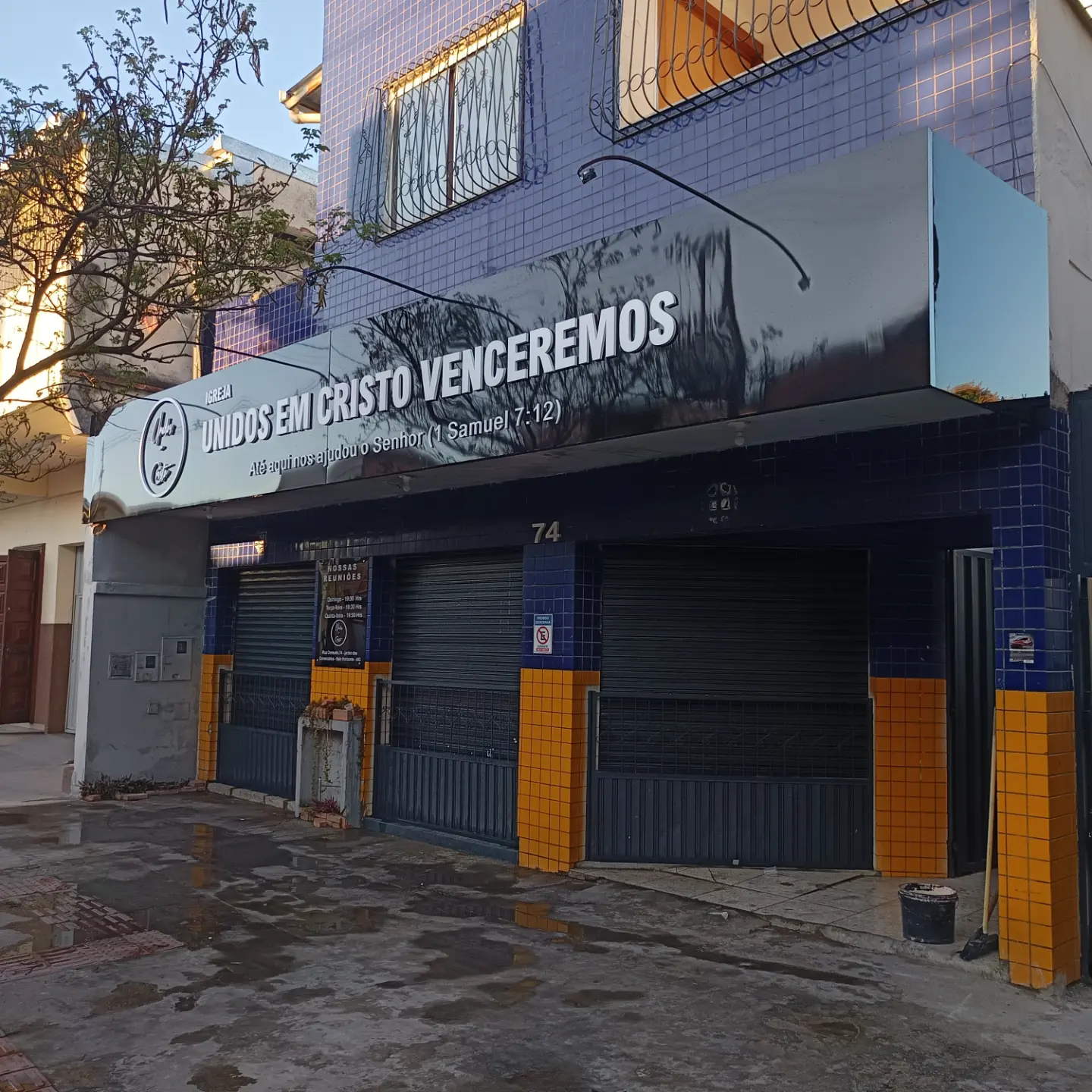 Fachada da Igreja Unidos em Cristo Venceremos durante o dia: testeira em ACM preto brilhante com letra caixa branca, ainda apagada