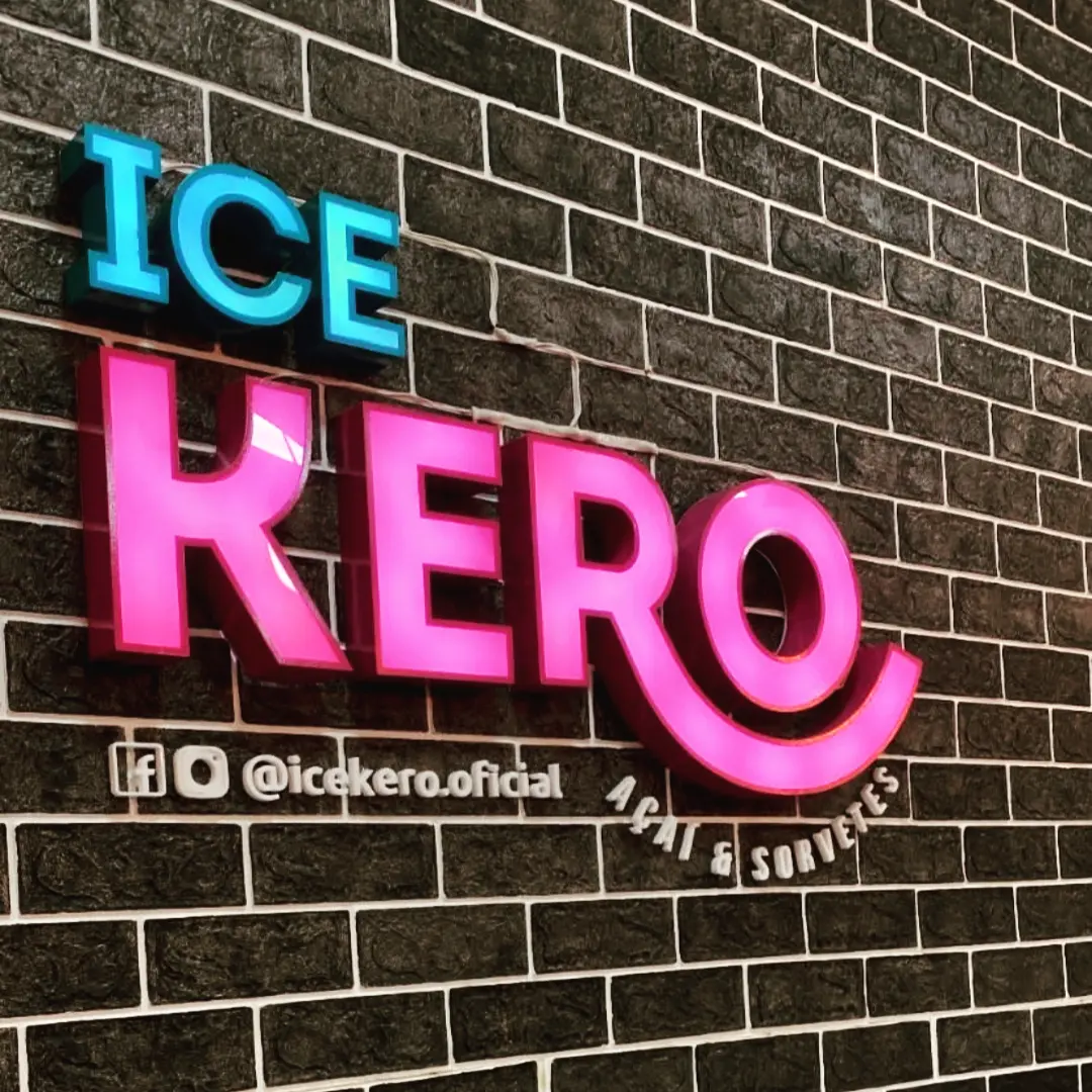 Letra caixa iluminada da Ice Kero em ciano e rosa sobre parede de tijolinho